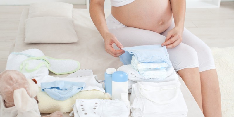 pregnant woman folding baby clothes
